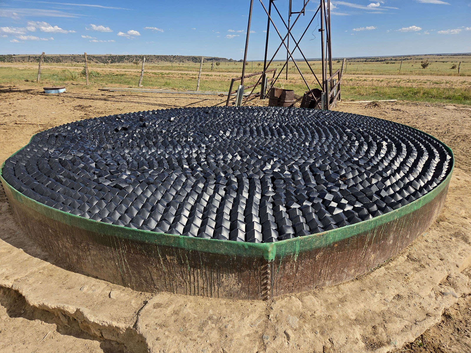 Ranch stock tank covered with VaporLok Rhombo shade balls beneath a windmill