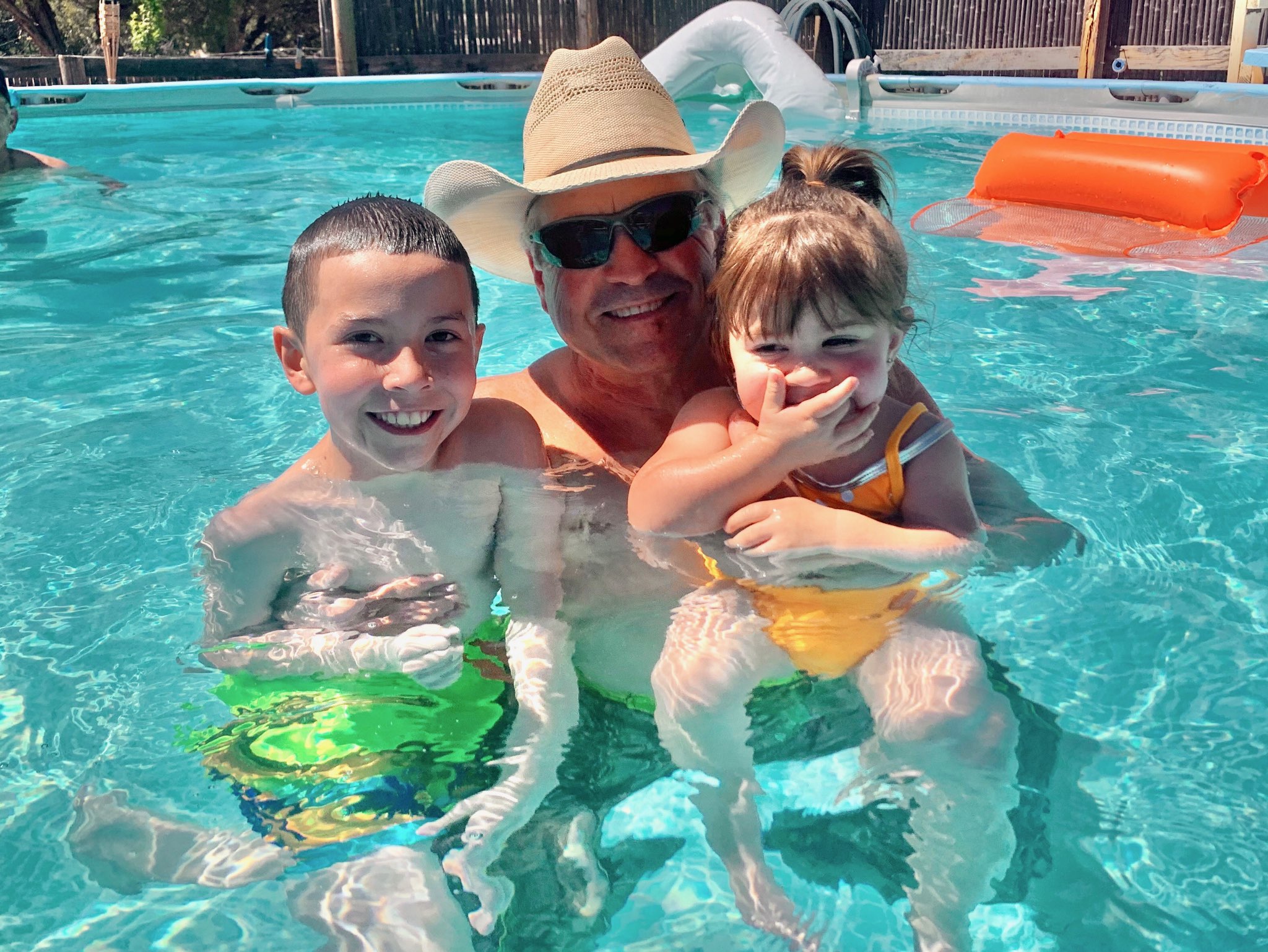 a grandfather swimming with two kids