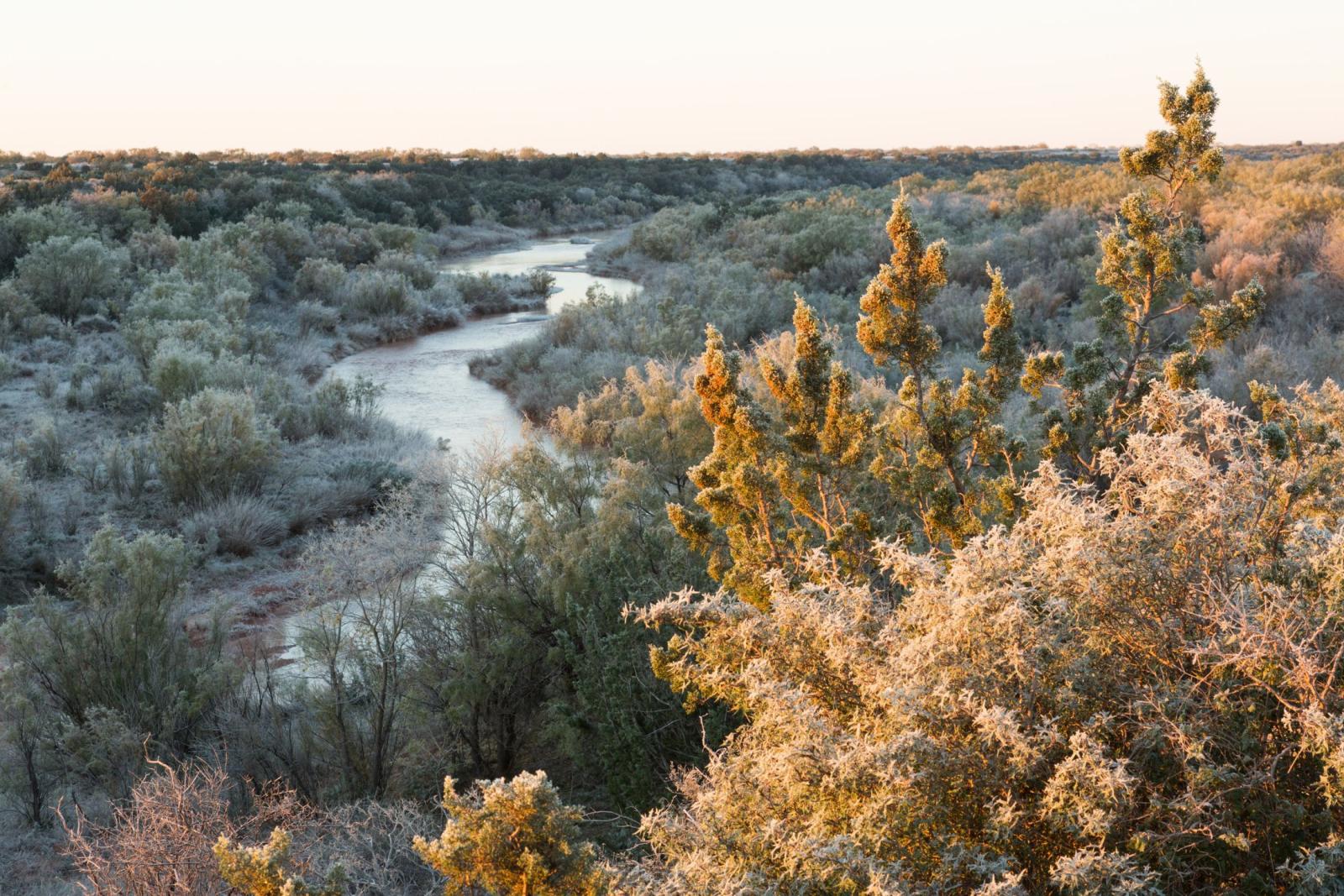 Evening light over a winding river and native ranch country at the Swenson Family Flat Top Ranch
